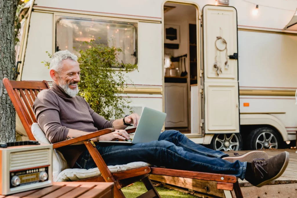 Laughing retiree sitting in front of caravan